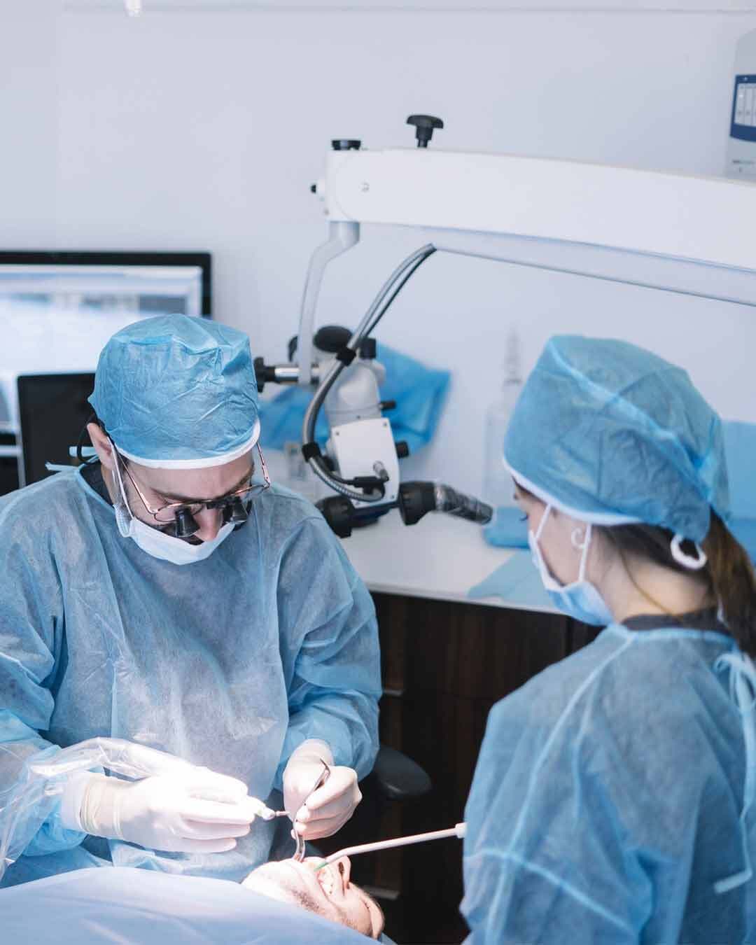 Gloved hands holding a surgical tray with six titanium implants and a vial of warm-amber plasma, Vampire Implants™ Protocol All-on-6, 5D Smiles